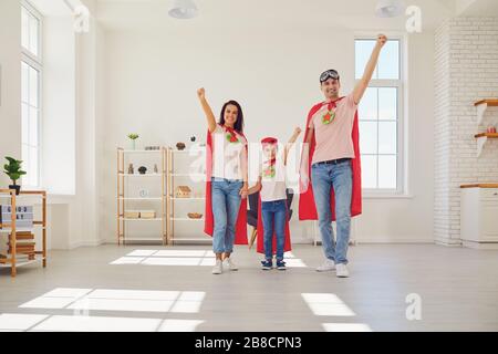 Happy family in costumi supereroi gioca avventura a casa. Foto Stock