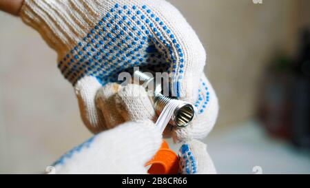 Primo piano di UN uomo è nastro sigillante avvolgere intorno a ferro acqua rubinetto vite. Foto Stock