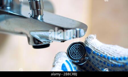Primo piano: L'aeratore è stato impostato per l'idraulico manuale con guanti. Installa un nuovo rubinetto d'acqua in bagno Foto Stock