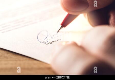 Uomo che scrive firma con penna su carta. Regolamento per acquisto, affare commerciale, prestito bancario o affitto appartamento. Firma contratto, accordo. Foto Stock