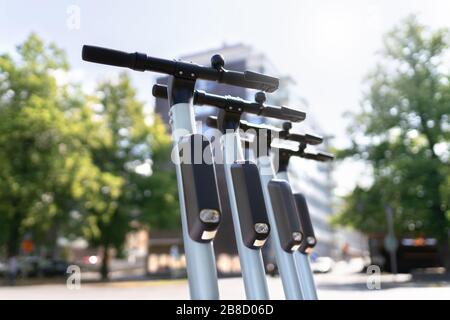 Molti scooter elettrici parcheggiati in città. E veicolo a noleggio. Trasporto urbano moderno e concetto di tecnologia. Foto Stock