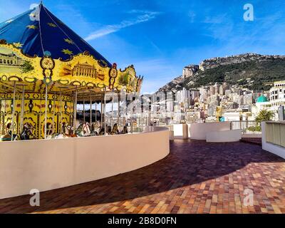 Vecchio stile, giostra e skyline del lussuoso Monte Carlo, Monaco, in una soleggiata giornata invernale. Foto Stock