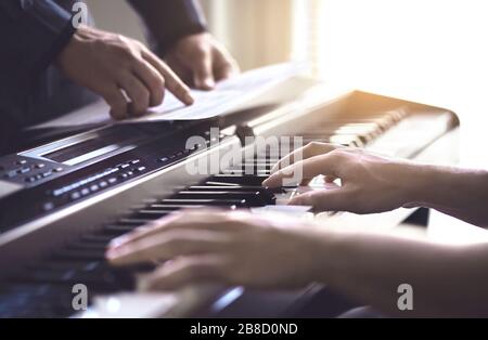 Insegnante di pianoforte e studente che pratica. Lezione di musica e corso a scuola. L'uomo impara a giocare con il tutor in classe. Mentore che insegna pianista. Pratica della band. Foto Stock