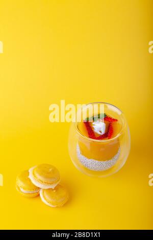 Budino di mango con semi di chia in vetro su sfondo giallo Foto Stock