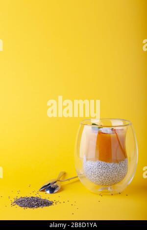 Budino di mango con semi di chia in vetro su sfondo giallo Foto Stock