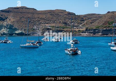 Akrotiri, Grecia - 19 luglio 2019: Barche riunite nella baia del Mar Egeo della spiaggia rossa di Akrotiri Foto Stock