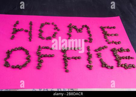 Home Office fatto di chicchi di caffè disposti su uno sfondo rosa Foto Stock