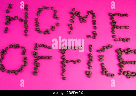 Home Office fatto di chicchi di caffè disposti su uno sfondo rosa Foto Stock