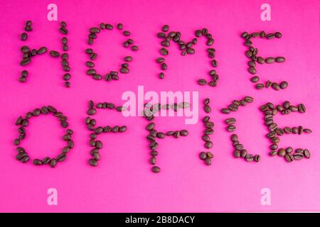 Home Office fatto di chicchi di caffè disposti su uno sfondo rosa Foto Stock