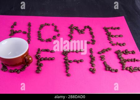 Home Office fatto di chicchi di caffè disposti su uno sfondo rosa Foto Stock