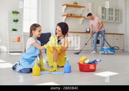 La famiglia felice pulisce la stanza nella casa. Foto Stock