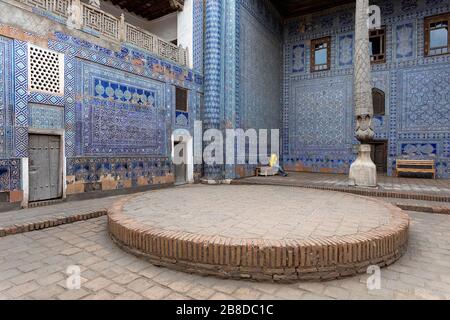 Donna che visita nel cortile con colonne scolpite e piastrelle dipinte, Tosh-Khovli o Palazzo di Khan, Khiva, Uzbekistan Foto Stock