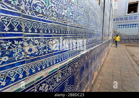 Donna che visita nel cortile con colonne scolpite e piastrelle dipinte, Tosh-Khovli o Palazzo di Khan, Khiva, Uzbekistan Foto Stock