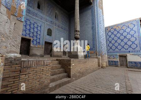 Donna che visita nel cortile con colonne scolpite e piastrelle dipinte, Tosh-Khovli o Palazzo di Khan, Khiva, Uzbekistan Foto Stock