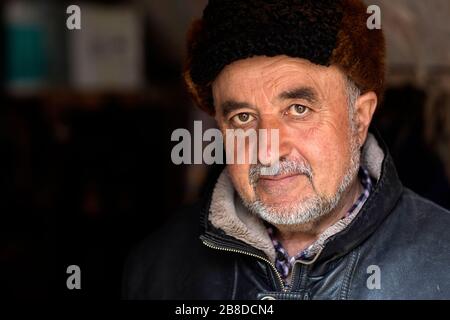 Uomo uzbeko che indossa un cappello di pelliccia e abiti tradizionali, Uzbekistan, Bukhara Foto Stock