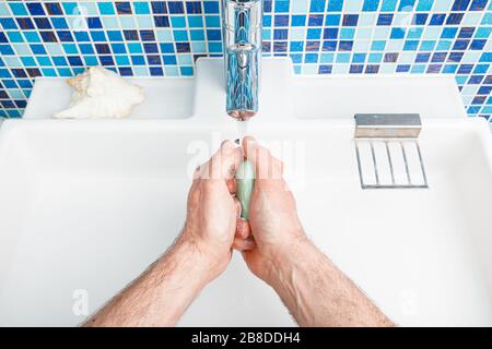 Uomo lavando le mani con sapone e acqua che attua le misure protettive di base contro la diffusione dell'epidermide del coronavirus Foto Stock