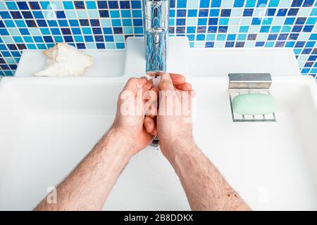 Uomo lavando le mani con sapone e acqua che attua le misure protettive di base contro la diffusione dell'epidermide del coronavirus Foto Stock