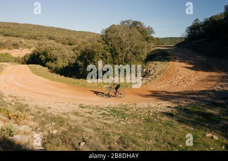 Il ciclista gira intorno a un angolo di ghiaia in un parco nazionale Foto Stock