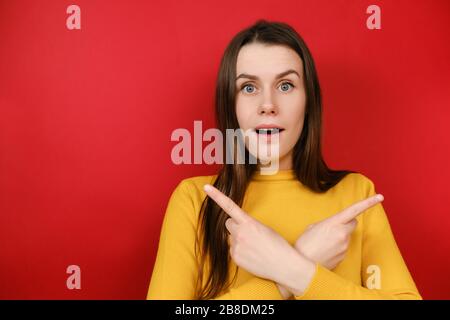 Interrogato giovane donna incerta incrociate le braccia sul petto, dà due varianti e pubblicizza il prodotto, indossa maglione Foto Stock