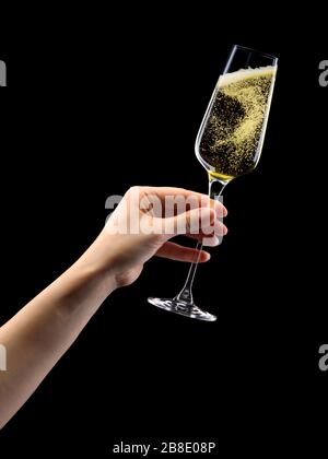 Donna mano che tiene un bicchiere di champagne frizzante isolato su nero. Foto Stock