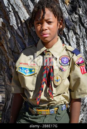 Cute Young African American boy pose contro l'albero indossando la sua divisa Boys Scouts of America a Tucson, Arizona, USA Foto Stock