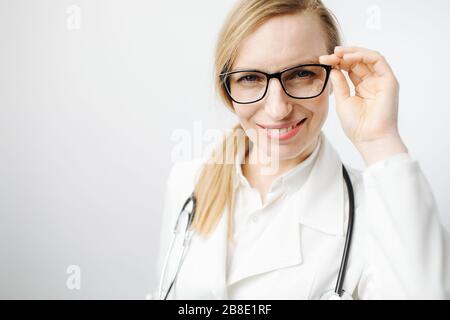 Donna in uniforme medica e occhiali che guardano la macchina fotografica Foto Stock