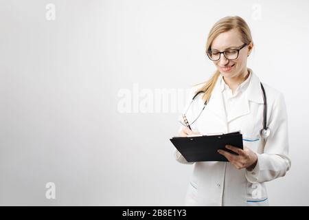 Sorridente medico femminile negli occhiali scrivere sulla clipboard Foto Stock