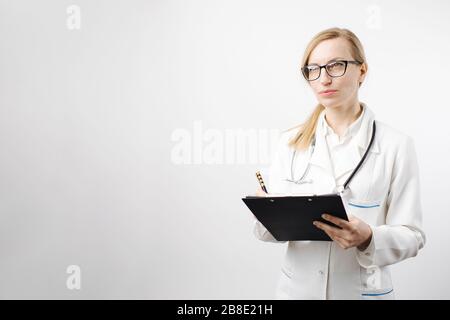 Medico femminile che scrive sulla clipboard e guardando da parte Foto Stock