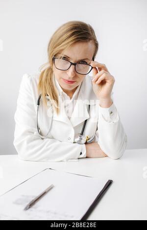 Stanco medico seduto in ufficio e guardando la macchina fotografica Foto Stock