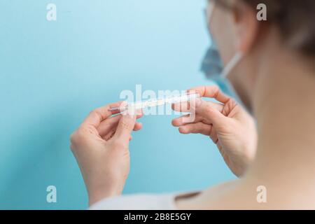 Donna in possesso di un termometro che misura la temperatura. Il concetto di malattie virali. Foto Stock