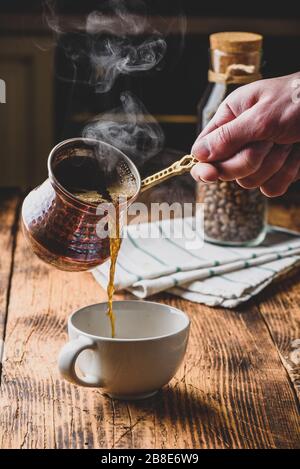 Versare il caffè turco in una tazza bianca Foto Stock