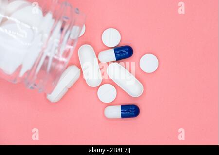 Primo piano delle pillole che fuoriescono dal flacone di pillola su sfondo rosa con spazio per le copie. Concetto di medicina . Foto Stock