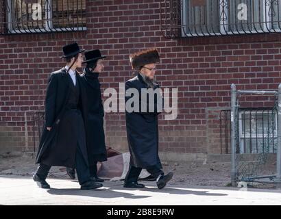 New York, NY - 21 marzo 2020: Uomini ebrei Hasidic Satmar camminano per le strade durante lo scoppio di Coronavirus nel quartiere di Williamsburg a Brooklyn Foto Stock