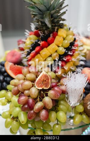 Tavola festosa frutta fresca diversa con ananas a fette, uva. Assortimento e celebrazione di frutta tropicale o altro evento. Foto Stock