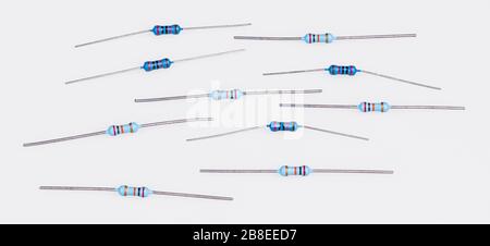 Set di resistenze miniaturizzate al carbonio blu su bianco. Gruppo di componenti elettrici a due terminali passivi. Bande colorate di codice colore standard elettronico. Foto Stock