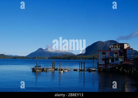Vista sulle montagne dall'acqua dal tranquillo porto, mare calmo e cielo azzurro. Foto Stock