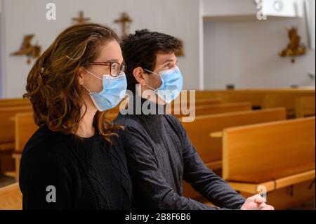 Una giovane coppia di maschere in faccia che prega in una chiesa durante la pandemia COVID-19. Bratislava, Slovacchia. Foto Stock