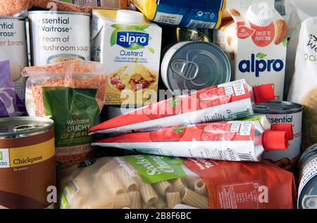 Barattoli stoccati e pacchetti di cibo essiccato accumulati sulla superficie di lavoro della cucina dopo la consegna a casa. Stoccaggio a causa della pandemia di Coronavirus. REGNO UNITO Foto Stock