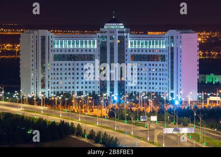 Imponente edificio curvo in marmo bianco ad Ashgabat, Turkmenistan. Empty Archabil Highway in primo piano con bei pali di lampada in una città esotica. Foto Stock