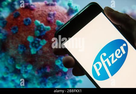In questa illustrazione della foto il logo della multinazionale farmaceutica americana Pfizer visualizzato su uno smartphone con un modello di computer del coronavirus COVID-19 sullo sfondo. Foto Stock
