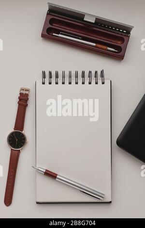 Sfondo minimalista per lo spazio di lavoro con laptop, penna, porta penna, orologio da polso e notebook. Struttura bianca per scrivania da ufficio. Concetto di lavoro, business, freelance. C Foto Stock