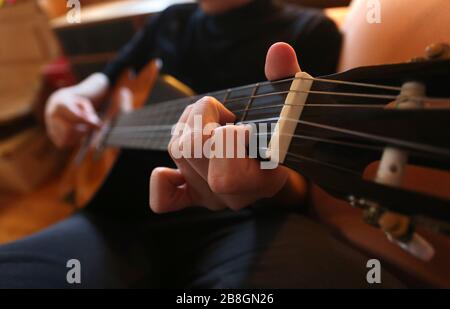 Kaufbeuren, Germania. 21 Mar 2020. Un uomo suona una chitarra nel salotto di casa sua. (A dpa-KORR: 'Lagerkoller o una possibilità? Come (sopravvivere) in isolamento' dal 22.03.2020). Credit: Karl-Josef Hildenbrand/dpa/Alamy Live News Foto Stock