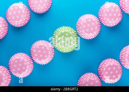 Casse per muffin. Custodie per torte. Vista dall'alto. Posa in piano. Sfondo blu. Vista piatta. Linea retta da un angolo all'altro. Custodia per cupcake. Ricucco colorato in carta Foto Stock