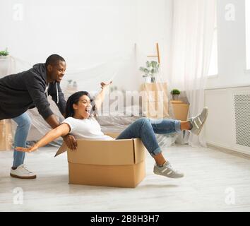 Il tipo africano americano spinge la scatola con una ragazza ridente Foto Stock
