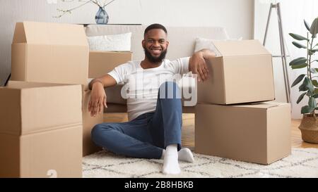 Molte scatole di cartone dal negozio online intorno sorridente ragazzo afro-americano Foto Stock