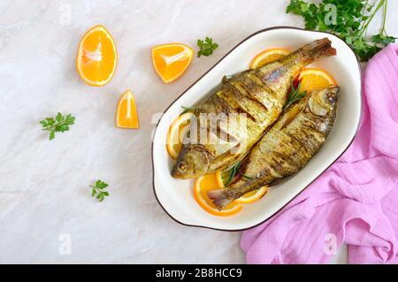 Pesce tostato con verdure e arance in una ciotola di ceramica. Vista dall'alto. Menu dietetico. Foto Stock
