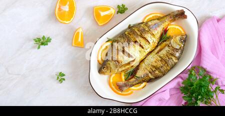 Pesce tostato con verdure e arance in una ciotola di ceramica. Vista dall'alto. Menu dietetico. Banner Foto Stock