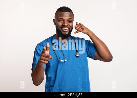 Giovane terapeuta amichevole che indica ai pazienti, chiedendo di chiamare Foto Stock