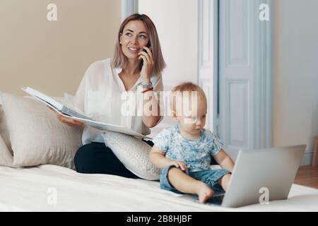 Business mom a parlare su un telefono cellulare. Multi-tasking, freelance e concetto di maternità Foto Stock