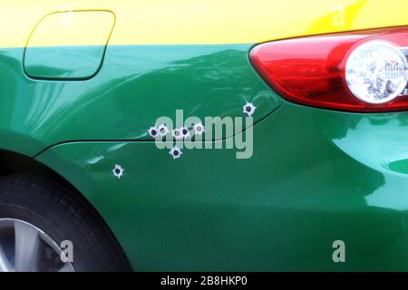 i segni bullets buco sul cofano della vettura, shrapnel bullet colpo foro rotto sulla superficie della vettura, sparare la vettura Foto Stock